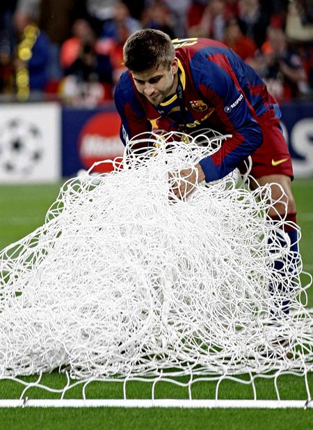El defensa del FC Barcelona Gerard Piqué recoge la red de una portería tras vencer el conjunto azulgrana al Manchester United. Foto: EFE