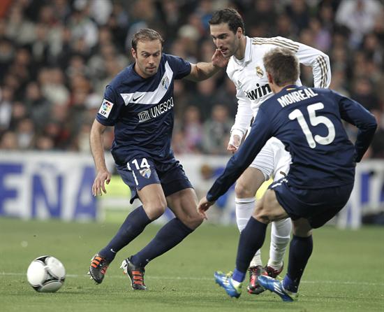 El delantero argentino del Real Madrid, Higuaín (c), golpea el balón ante los jugadores del Málaga. Foto: EFE