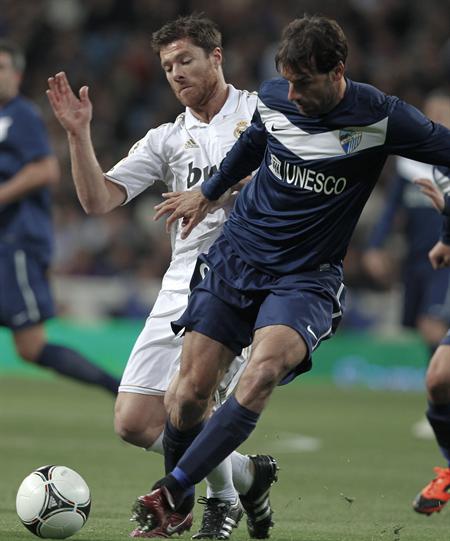 El delantero holandés del Málaga, Van Nistelrooy (d), disputa el balón ante el centrocampista del Real Madrid, Xavi Alonso. Foto: EFE