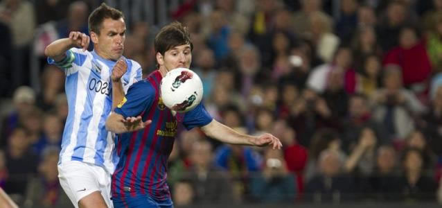 El portugués del Málaga Sergio Paulo Barbosa 'Duda' (d) comete penalti sobre el delantero argentino del FC Barcelona Leo Messi. Foto: EFE