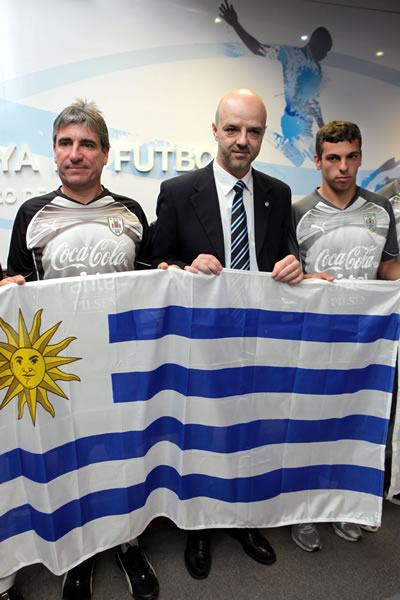 El seleccionador uruguayo Juan Verzeri (i), el viceministro de Turismo y Deporte, Antonio Carámbula (c), y el futbolista Gonzalo Bueno (d), posan con la bandera. Foto: EFE