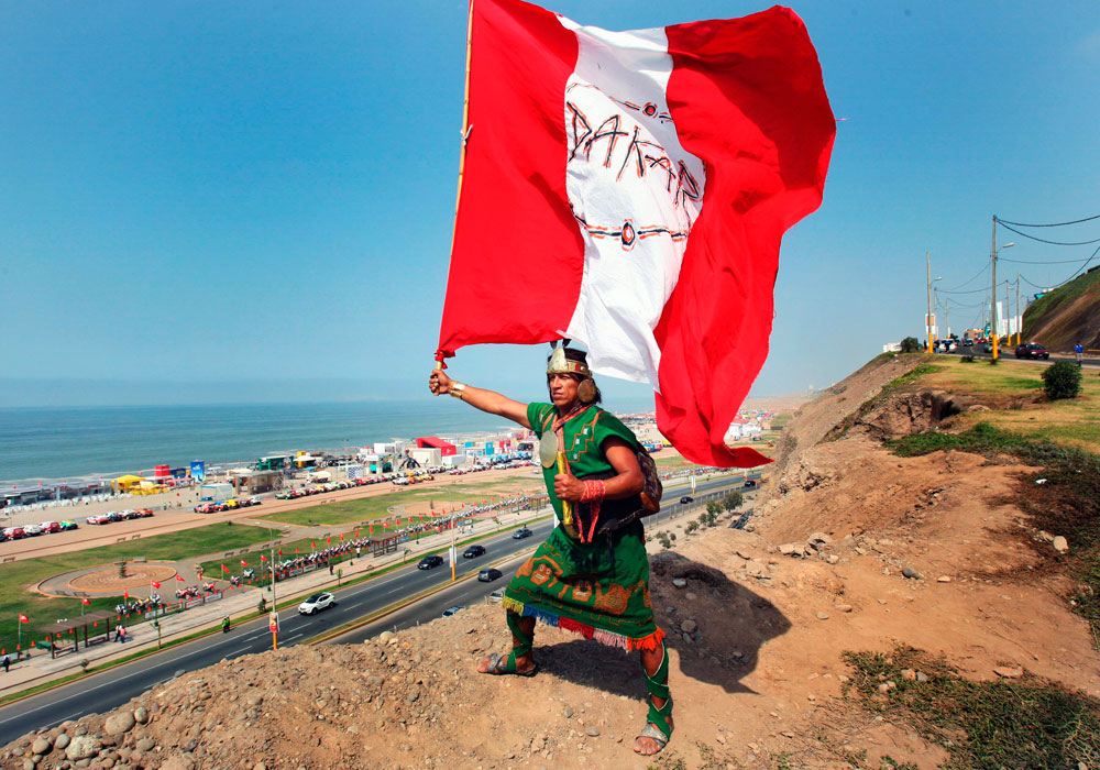Un poblador de la limeña zona de Huaycán ondea una bandera de Perú anunciando la llegada del Dakar 2013. Foto: EFE