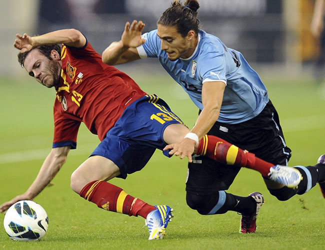 El español Juan Mata (izda) pelea por el control del balón con el uruguayo Martín Cáceres. Foto: EFE