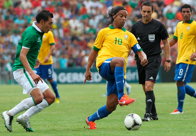 Ronaldinho Gaúcho (c) disputa el balón con Ronald Eguino (i). Foto: EFE