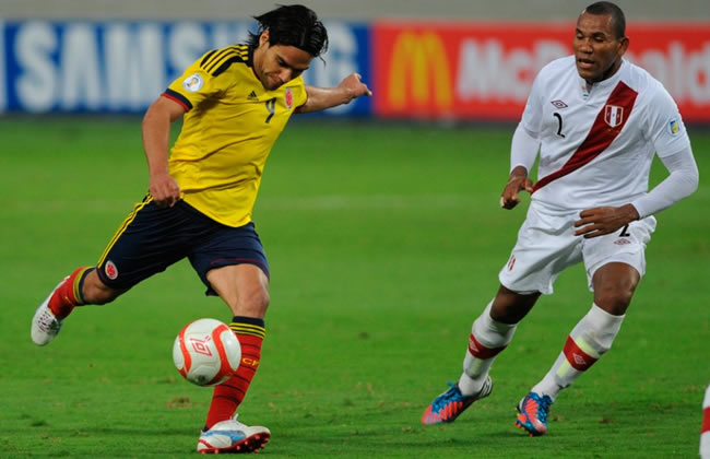 El delantero colombiano Radamel Falcao García va a patear el balón ante John Galliquio del Perú. Foto: EFE