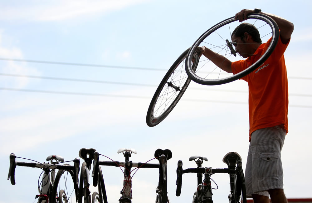 Un asistente técnico sostiene dos ruedas durante la Vuelta a Colombia. Foto: EFE