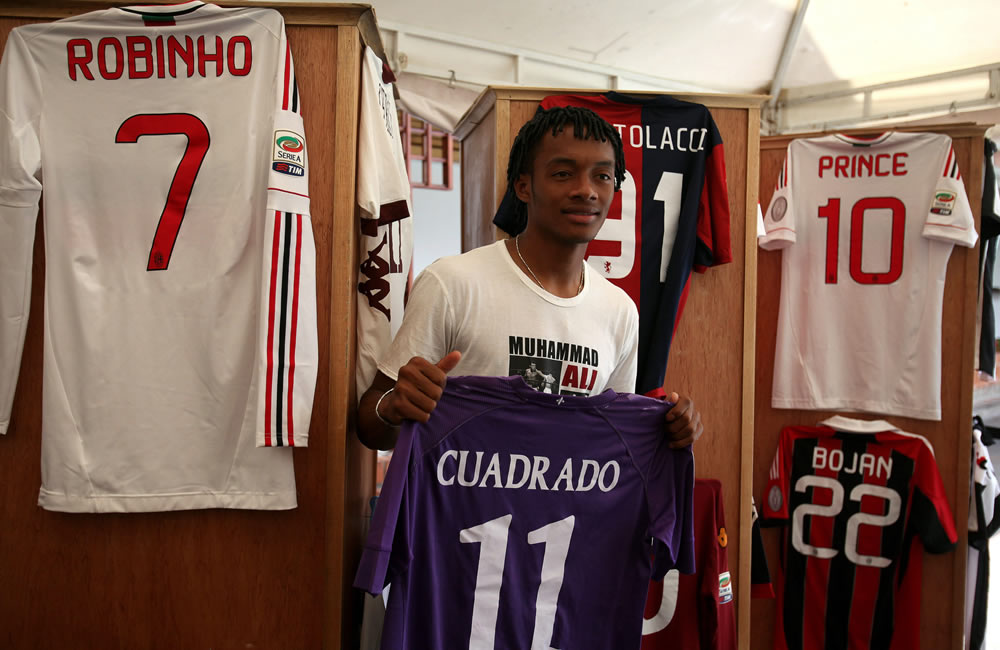 Juan Guillermo Cuadrado exhibe una de las camisetas de figuras del fútbol internacional que subastó. Foto: EFE