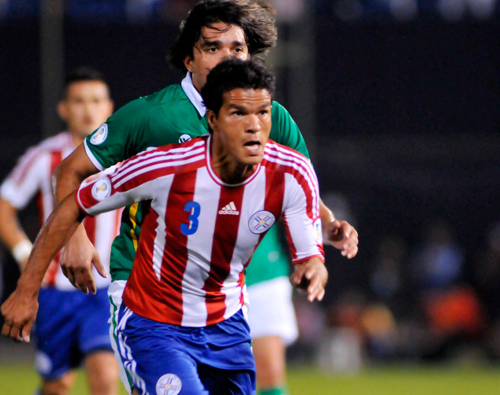 El jugador de la selección paraguaya, Salustiano Candia, disputa el balón con Marcelo Martins de Bolivia. Foto: EFE