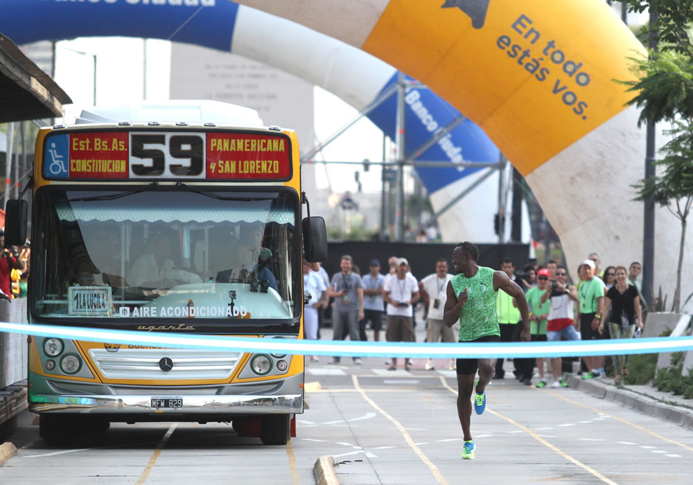 El plusmarquista jamaiquino Usain Bolt corre mano a mano contra un colectivo en una carrera de 80 metros por el carril del Metrobús en la famosa avenida 9 de Julio del centro de Buenos Aires. Foto: EFE