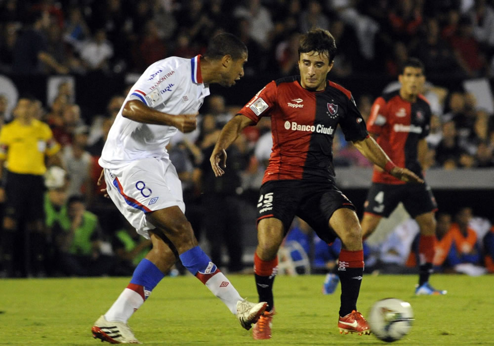 El jugador de Newell's Old Boys Fabián Muñoz (c) marca a Diego Arismendi (i), de Nacional. Foto: EFE