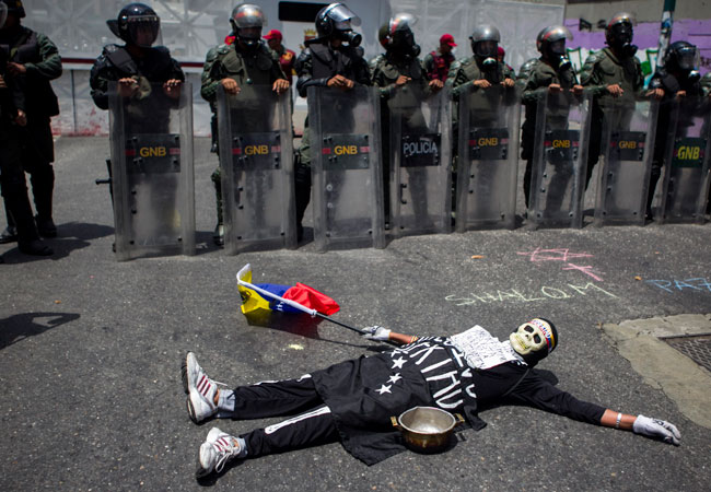 Una hombre protesta frente a miembros de la Guardia Nacional Bolivariana durante una manifestación con ollas vacías en Caracas. Foto: EFE
