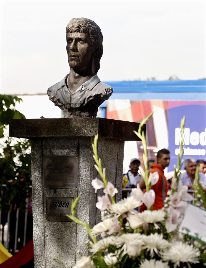 Detalle de un busto del futbolista Andrés Escobar roedado de flores. Foto: EFE