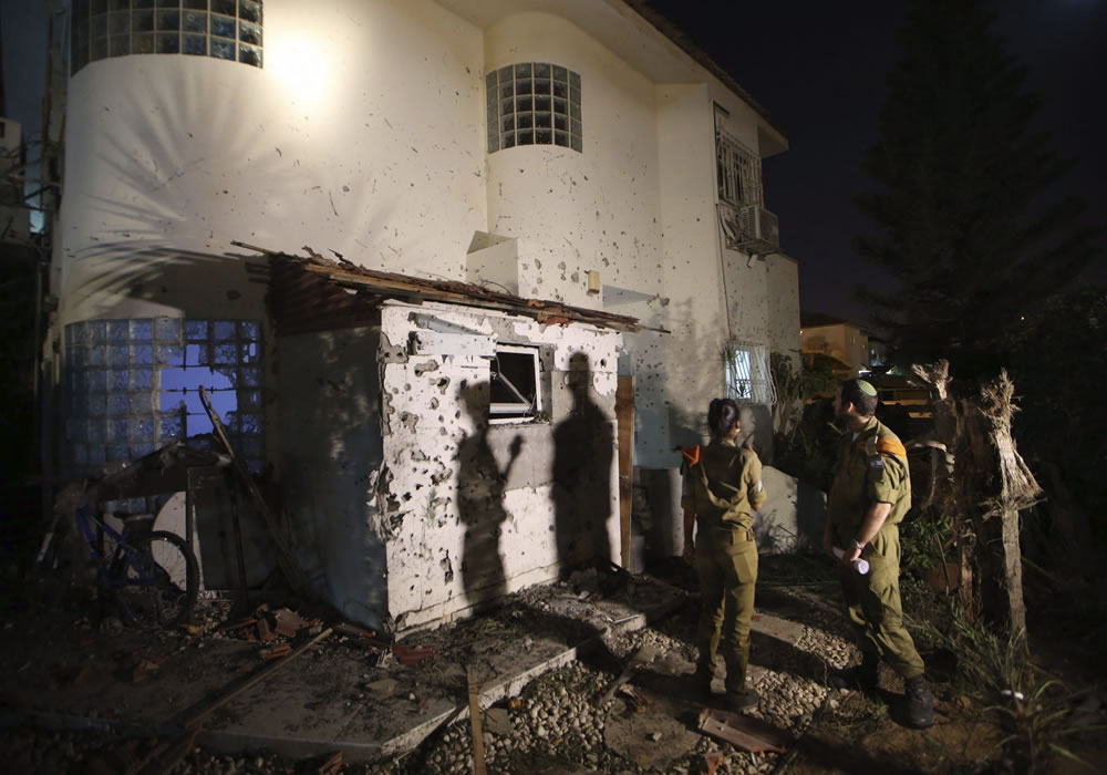 Varios oficiales de seguridad israelíes inspeccionan los daños de una casa tras haber impactado sobre ella directamente un misil desde la Franja de Gaza. Foto: EFE