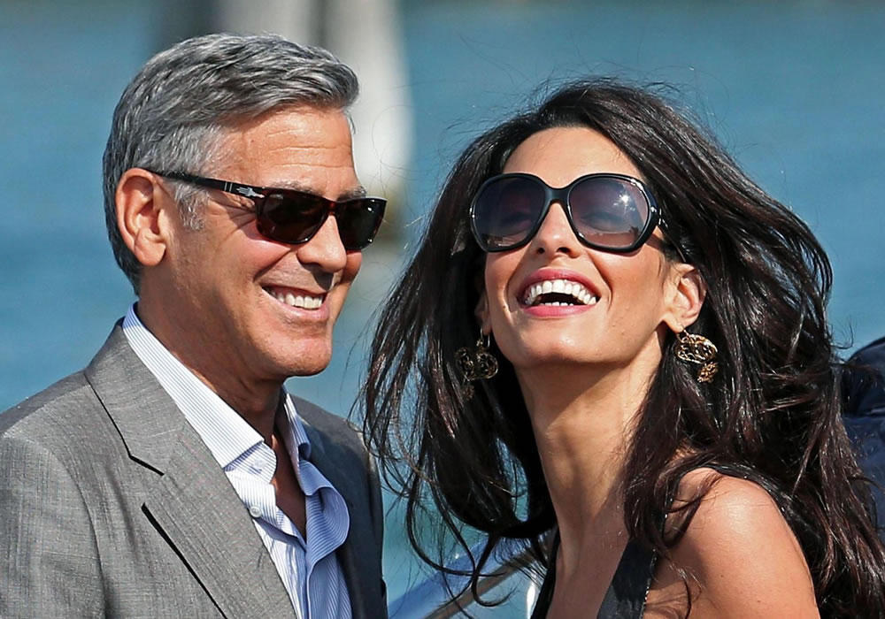 El actor estadounidense, George Clooney (izda), y su prometida, Amal Alamuddin (dcha), a su llegada por barco a Venecia. Foto: EFE