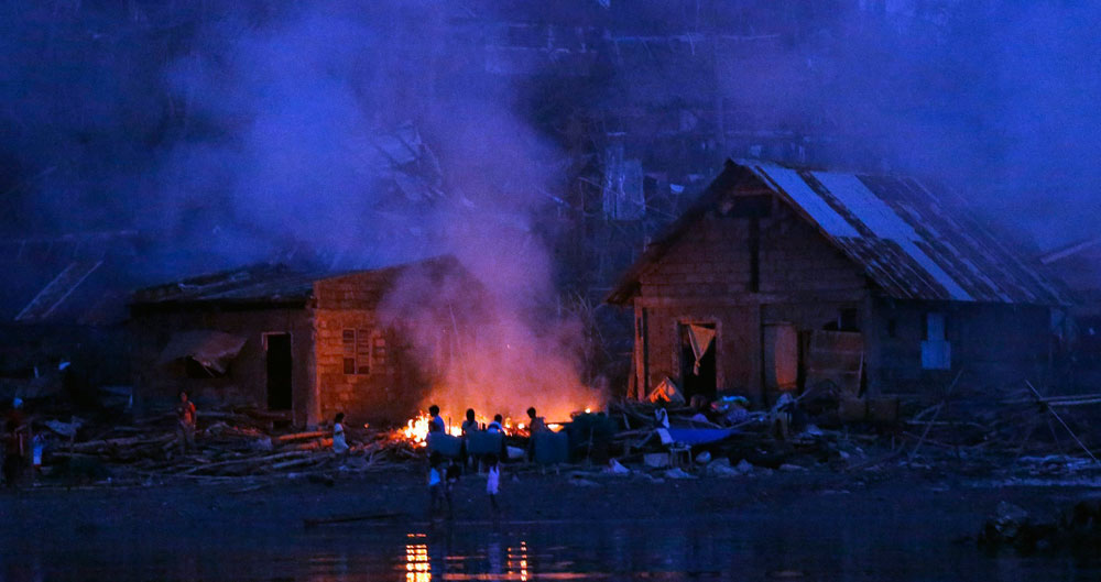 Supervivientes del tifón Hagupit queman basura y escombros para calentarse en el exterior de unas viviendas en la localidad de Villarial, en la isla de Samar, Filipinas. Foto: EFE