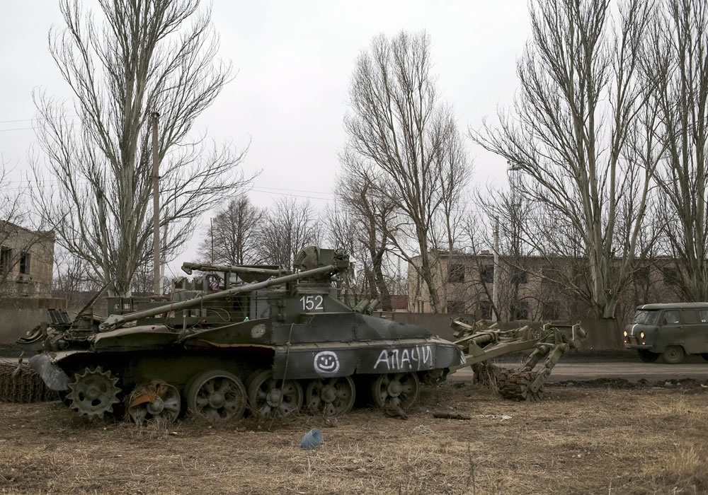 Un coche circula cerca de un vehículo militar blindado en la localidad de Ocheretyane, en la zona de Donetsk (Ucrania). Foto: EFE