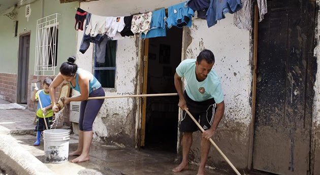Una familia limpia la entrada de su casa tras avalancha en Salgar, Antioquia. Foto: EFE