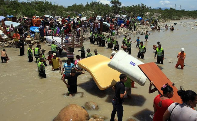 Cientos de colombianos cargan sus pertenencias por el río Táchira desde Venezuela hacia el sector La Parada (Colombia). Foto: EFE