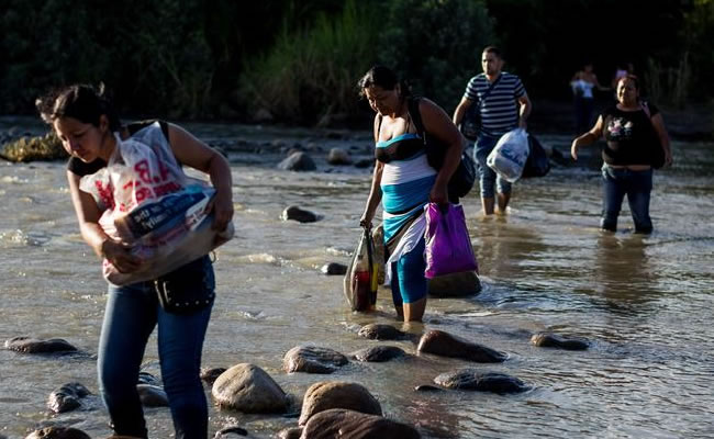 Grupo de personas cruzan el río Táchira, que divide a Venezuela y Colombia. Foto: EFE