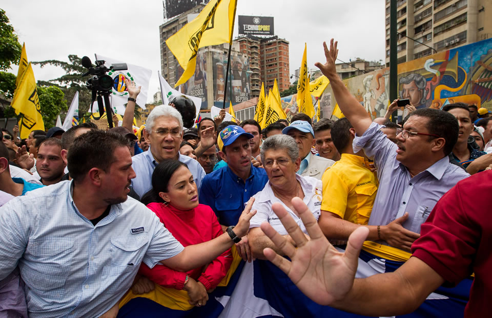 El líder opositor Henrique Capriles es auxiliado por sus colaboradores tras salir afectado por gases lacrimógenos en una manifestación. Foto: EFE