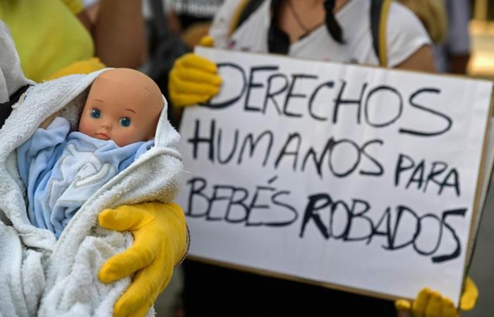 Un grupo de manifestantes con muñecas y pancartas protestan frente a un tribuna de Madrid en el primer día del juicio por los bebés robados. Foto: AFP