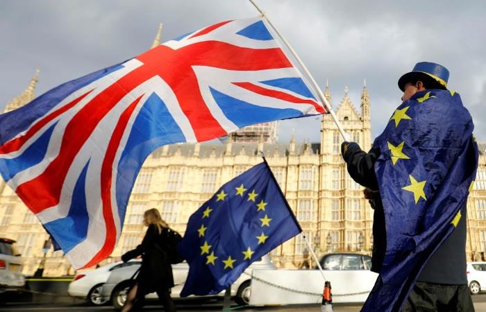 Un hombre contrario al Brexit se manifiesta frente al Parlamento cubierto por una bandera europea y haciendo ondear una bandera británica. Foto: AFP