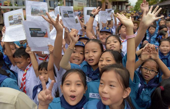 Estudiantes tailandeses sonríen mientras sostienen fotos de los 12 niños y un entrenador de fútbol frente al hospital después de que el grupo fue rescatado. Foto: AFP