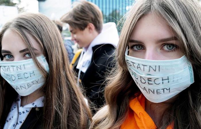 Dos jóvenes portan mascarillas con el mensaje 'El último aliento del planeta', en Polonia. Foto: EFE