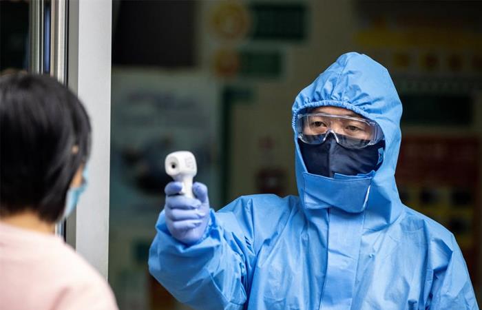 Agente de seguridad revisa la temperatura de una ciudadana china. Foto: EFE