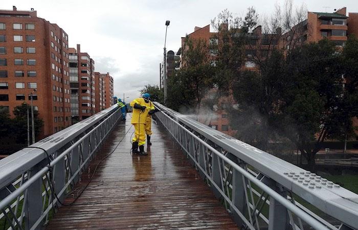 Trabajadores de la limpieza desinfectan un puente en el norte de Bogotá. (). Foto: EFE