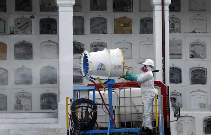 Un trabajador dirige un cañón nebulizador de desinfectante en un cementerio en Bogotá. (). Foto: EFE
