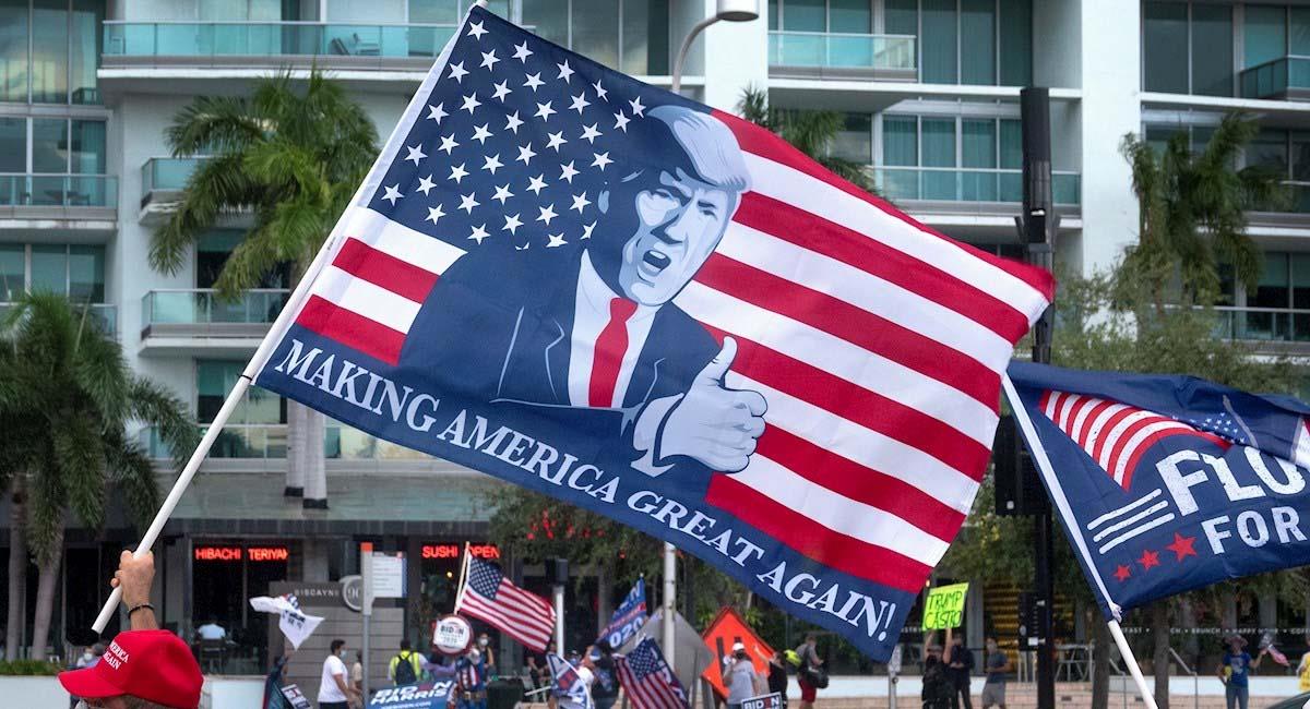 Seguidor de Donald Trump lleva una bandera de su campaña presidencial. Foto: EFE