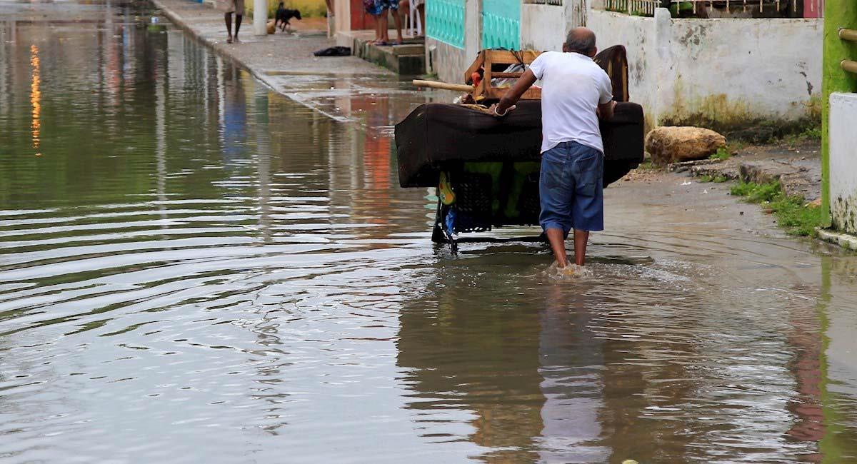 Un hombre empuja una carreta por una calle inundada por las lluvias fuertes en Cartagena. Foto: EFE