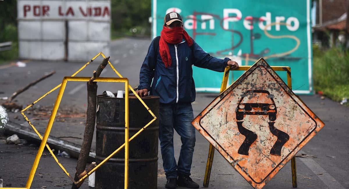 Manifestante bloquea la carretera entre los municipios de Buga y Tuluá, en el Valle del Cauca. Foto: EFE