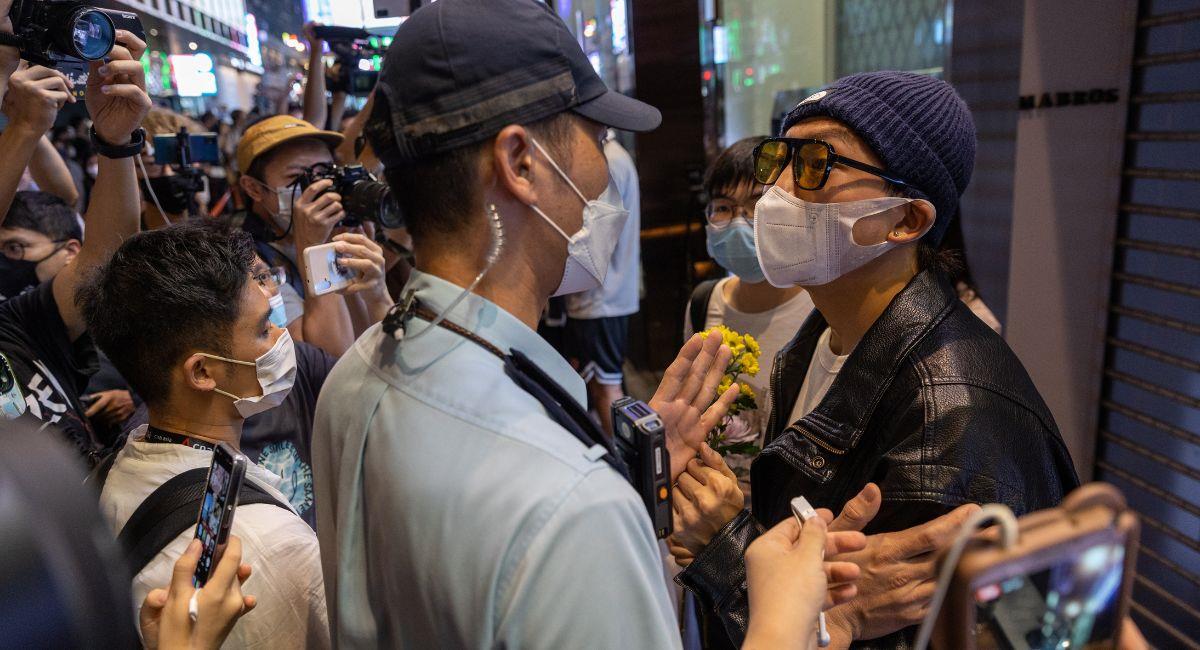 La policía revisa a los dolientes durante una vigilia por las víctimas de la política de cero COVID de China y las víctimas del incendio de Urumqi en Hong Kong, China. Foto: EFE EFE/EPA/JEROME FAVRE