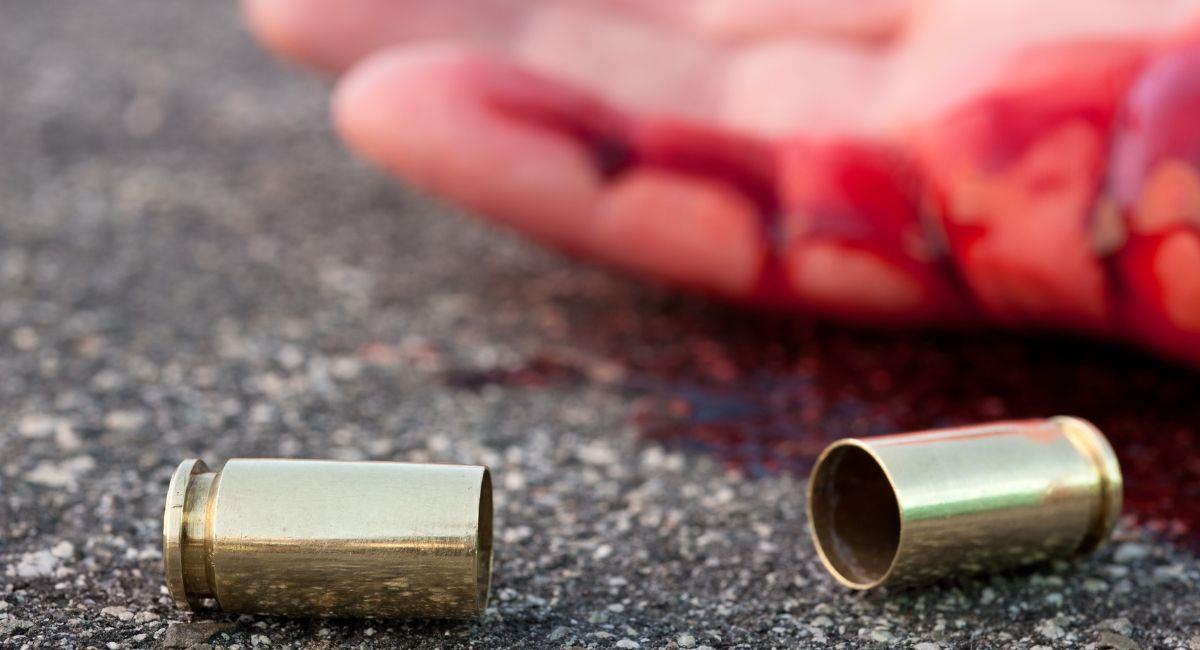 Foto de un hombre disparó en las calles con el casquillo de una bala tendido al lado de una mano sangrienta. Foto: Shutterstock